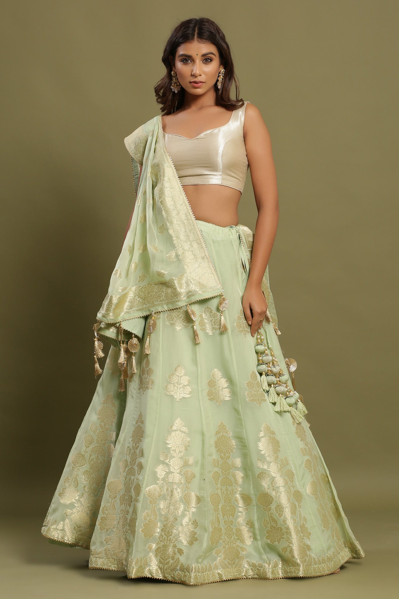 Shop green self-embroidered Zari lehenga set. It has a solid off-white blouse with tassels attached to the dupatta. Pair it with beautiful jewelry to enhance your look. Shop online from Pure Elegance.