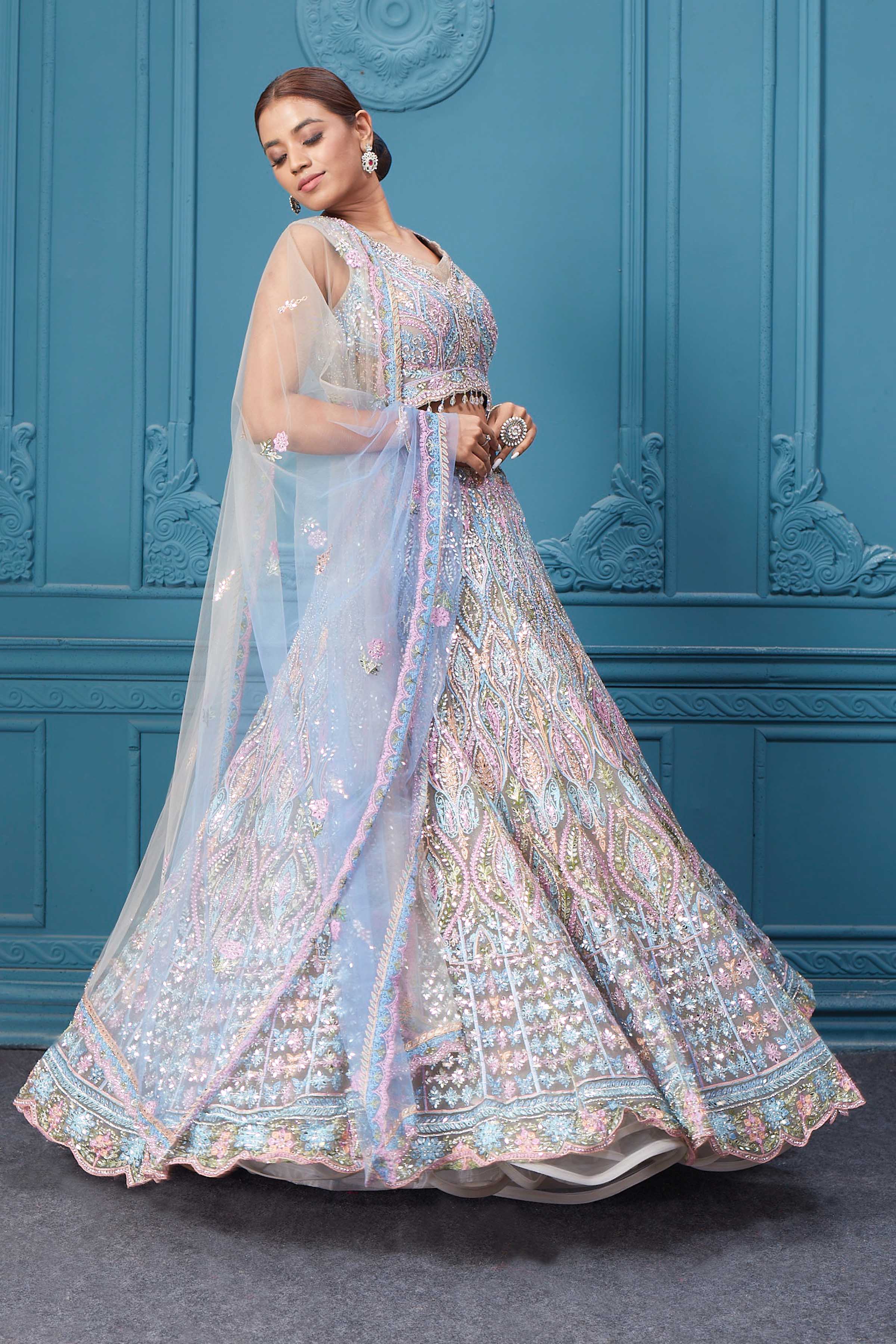 Shop this light blue and pink lehenga with heavy floral and sequin embroidery. Dazzle on weddings and special occasions with exquisite Indian designer dresses, sharara suits, Anarkali suits, bridal lehengas, and sharara suits from Pure Elegance Indian clothing store in the USA. Shop online from Pure Elegance.