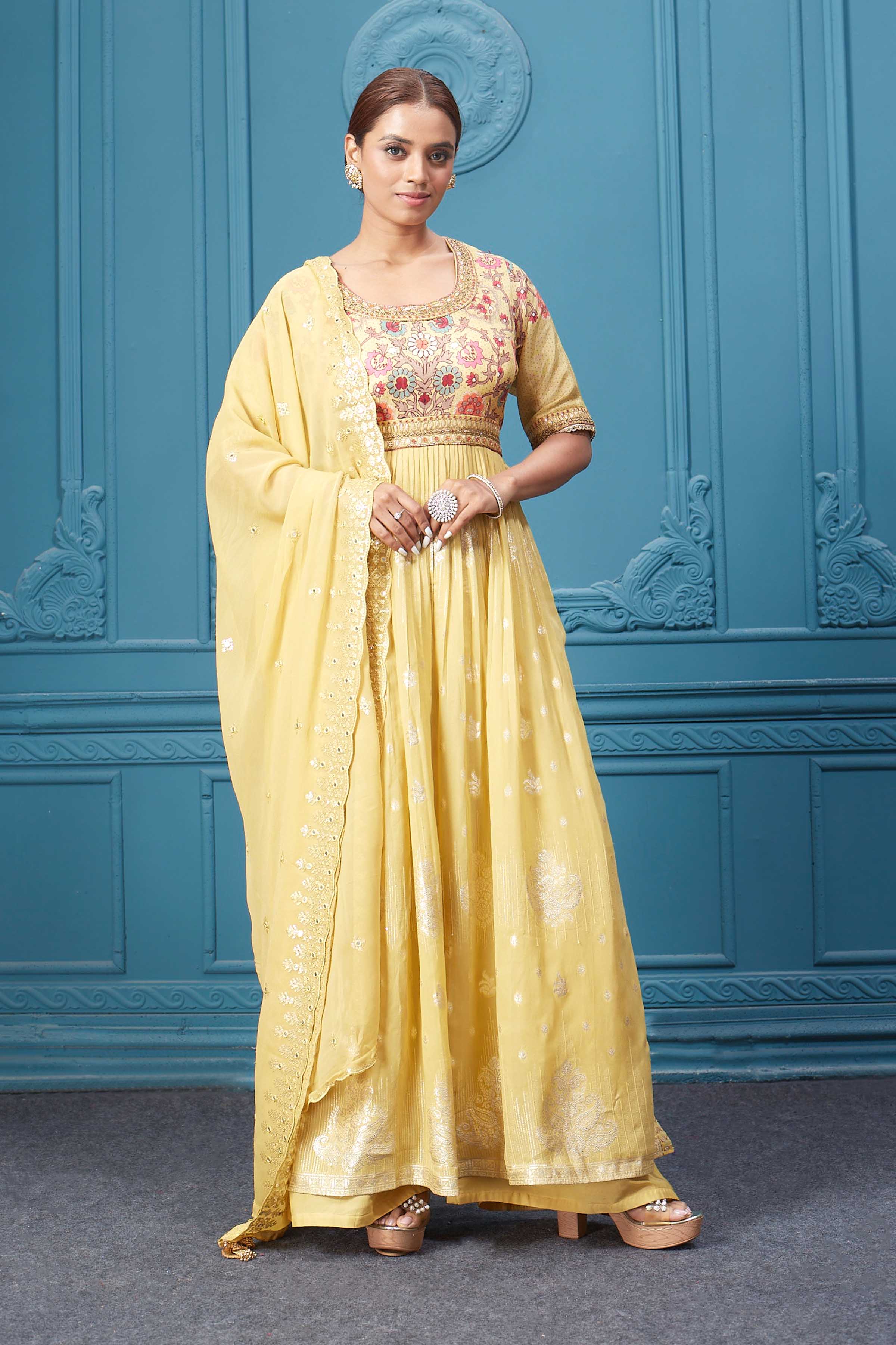 Shop a yellow naira cut suit set with mirror work and embroidered kurta, plazzo, 3/4th sleeves, and beautiful mirror work embroidered dupatta. Dazzle on special occasions with exquisite Indian designer dresses, sharara suits, Anarkali suits, bridal lehengas, and sharara suits from Pure Elegance Indian clothing store in the USA. Shop online from Pure Elegance.