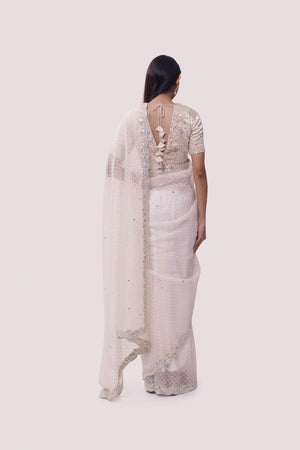 Shop a Beautiful off-white organza saree featuring threadwork and sparse embellishments. It comes with an embroidered blouse. Make a fashion statement on festive occasions and weddings with designer sarees, designer suits, Indian dresses, Anarkali suits, palazzo suits, designer gowns, sharara suits, and embroidered sarees from Pure Elegance Indian fashion store in the USA.