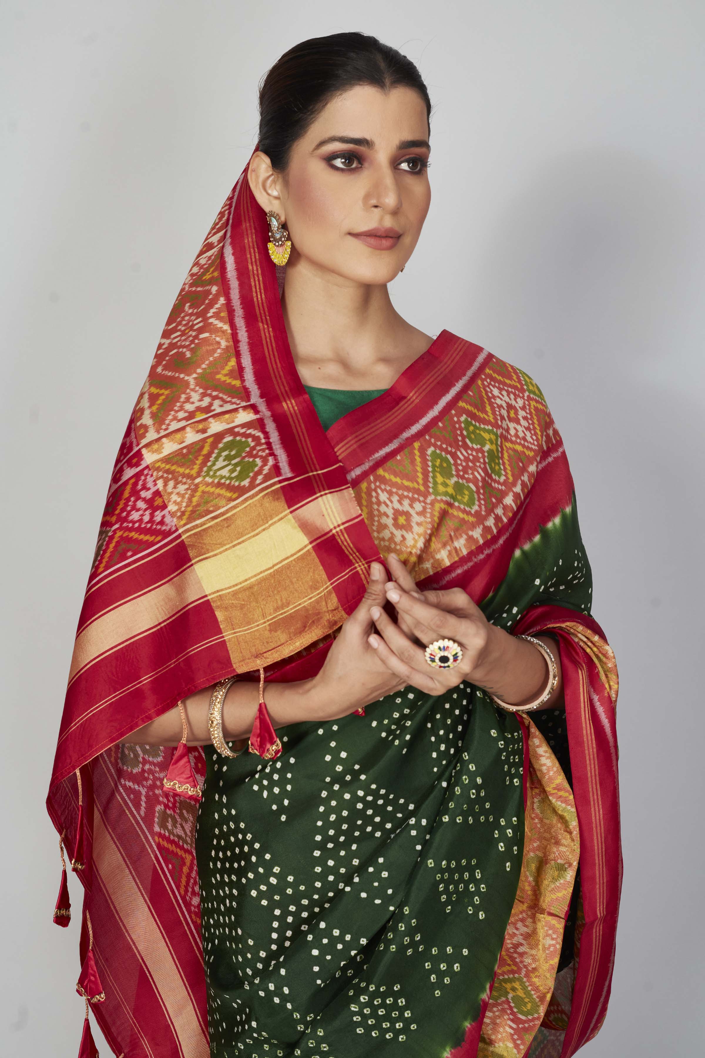 Shop bottle green silk Bandhej sari online in USA with red border. Look your best on festive occasions in latest designer saris, pure silk saris, Kanjivaram silk sarees, handwoven saris, tussar silk sarees, embroidered sarees from Pure Elegance Indian clothing store in USA.-closeup