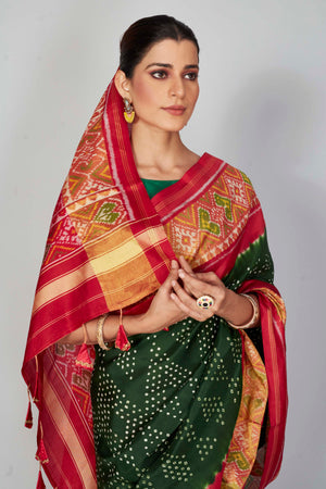 Shop bottle green silk Bandhej sari online in USA with red border. Look your best on festive occasions in latest designer saris, pure silk saris, Kanjivaram silk sarees, handwoven saris, tussar silk sarees, embroidered sarees from Pure Elegance Indian clothing store in USA.-closeup