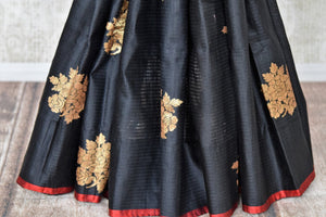 Shop black borderless tussar Benarasi saree online in USA with golden floral buta. Shine bright in best of Indian designer sarees from Pure Elegance Indian fashion store in USA on special occasions. Choose from a splendid variety of Banarasi sarees, pure handwoven saris. Shop online.-pleats